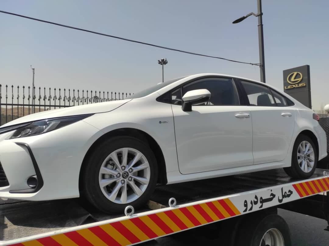 خودروی سواری سفید روی کفی خودروبر سیروان در محوطه‌ی یک نمایندگی خودرو